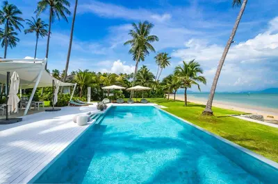 a swimming pool next to a beach with palm trees at Baan Klong II in Ko Yao Noi