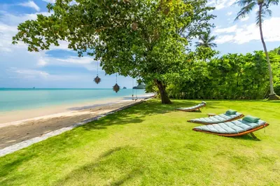 two boats sitting on the grass next to the beach at Baan Klong in Ko Yao Noi