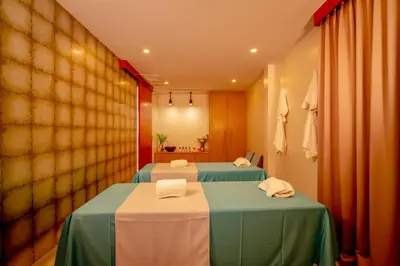 two beds in a hotel room with two tables at Baan Kloi IV in Ban Na Tai
