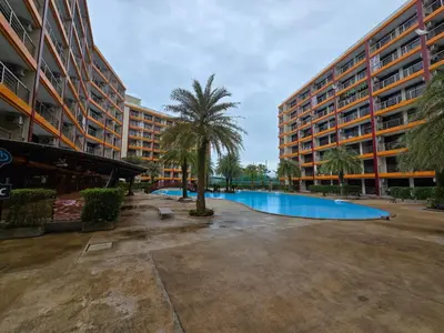 a large building with a palm tree and a swimming pool at 777 Beach Condotel in Mai Khao Beach