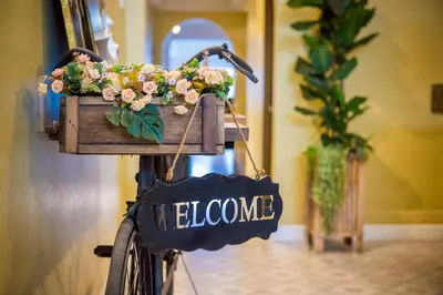 a bike with a basket filled with flowers and a welcome sign at 113 Yellow House Hostel in Phuket Town