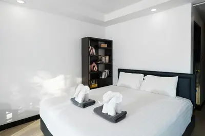 a bedroom with a white bed with two white towels at Noksawan Villa by G Estate in Rawai Beach