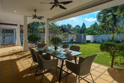 a patio with a table and chairs and a garden at Noksawan Villa by G Estate in Rawai Beach