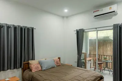 a bedroom with a bed with black curtains and a balcony at Jampun Pool Villa in Klong Muang Beach