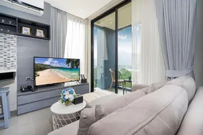 a living room with a white couch and a tv at Tropics Kamala Hill View Apartment CTG D704 near Beach and Fantasea in Kamala Beach