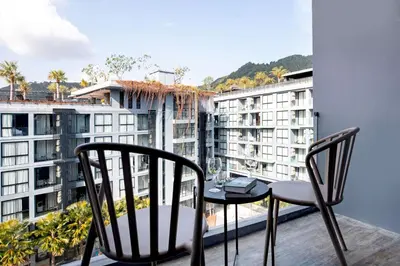 a balcony with two chairs and a table at Fun, Beach & Topical Vibes! Pool View 2BR Apartment CTG P603-4 in Tropics Kamala Residence in Kamala Beach