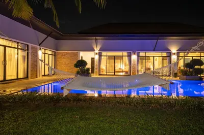 a hammock in front of a house at night at Bua Sawan - 4 Bedrooms Pool Villa in Ban Pak Lak