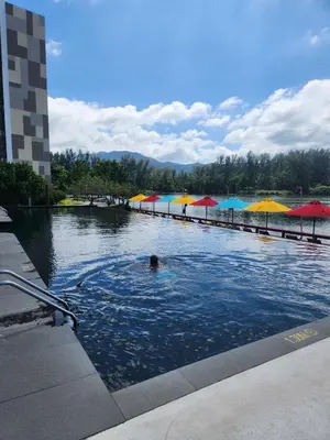 a person swimming in a pool with umbrellas at Cassia Loft Laguna Phuket Bang Tao Beach in Laguna Phuket
