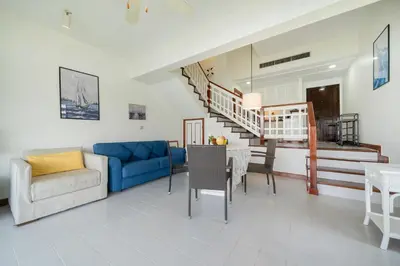 a living room with a blue couch and a table at Allamanda Townhouse Laguna Phuket Bang Tao Beach in Laguna Phuket