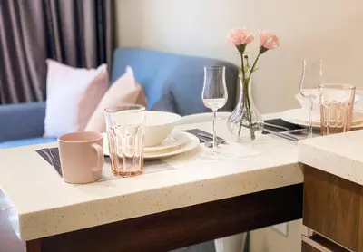 a table with plates and glasses and a vase of flowers at ARIA Condo 1BR Pool View NBC Nai Harn in Phuket Town