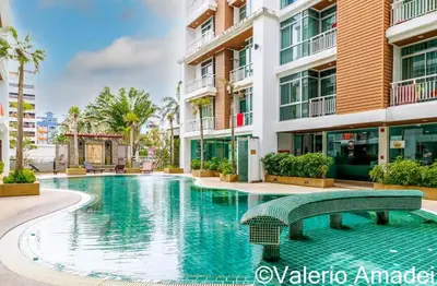 a swimming pool with a green bench in front of a building at OMNIAPHUKET - Pool access 3 bedrooms apartment in Patong Beach