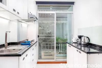 a kitchen with white cabinets and a large window at OMNIAPHUKET - Pool access 3 bedrooms apartment in Patong Beach
