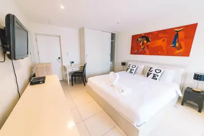a white bedroom with a bed and a desk at Patong Condotel Penthouse 2 bedroom in Patong Beach