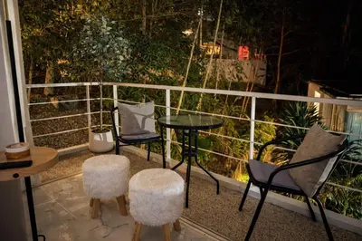 a balcony with two chairs and a table and two stools at Cozy Retreat Near Beach and Pools in Kamala Beach