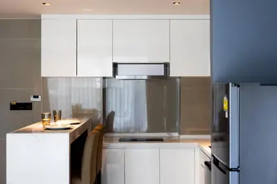 a kitchen with white cabinets and a stainless steel refrigerator at Suite Elio 1BR PoolsGym Shuttle to Nai Harn in Rawai Beach