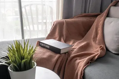 a book sitting on top of a blanket on a couch at Suite Ruse 1BR Rooftop Pool ViewCitygate Kamala in Kamala Beach