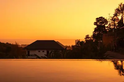 a view of a house from the water at sunset at Karon Bliss Sea View Villa with Private Pool in Karon Beach