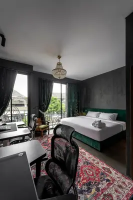 a bedroom with a bed and a table and chairs at Boss Level Gaming Hotel in Rawai Beach