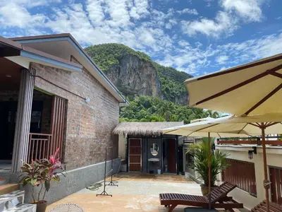 a building with a patio with a mountain in the background at Kalamung Resort and Pool villas in Ao Nang Beach