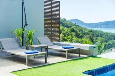 a patio with chairs and a table and a pool at Sirirat Sea-view Villa in Patong Beach