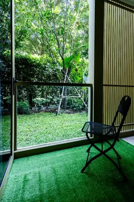 a chair sitting on a green carpet in front of a window at Private garden Laguna beachside 150 m Bangtao in Bang Tao Beach