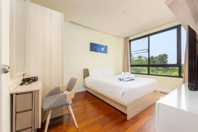 a bedroom with a bed and a chair and a window at LAGO APARTMENTS BY TROPICLOOK in Nai Harn Beach