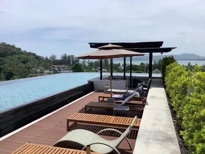 a deck with chairs and an umbrella and a pool at Superb Apartment! 5 Mins to the Beach in Surin Beach