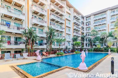 an apartment building with a swimming pool and palm trees at OMNIAPHUKET - Pool View Apartment at Phuket Villa Patong Beach in Patong Beach
