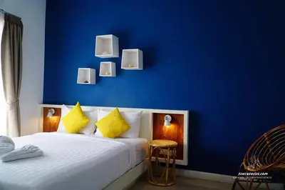 a bedroom with a blue wall and a bed with yellow pillows at Chill House at Naiyang in Nai Yang Beach