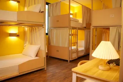 a room with bunk beds with a lamp and a table at Bed & Beach Hostel Karon in Karon Beach