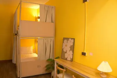 a room with a bunk bed with a desk and a mirror at Bed & Beach Hostel Karon in Karon Beach