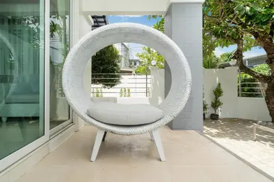 a white wicker chair sitting on a porch at 7BR Grand Pool Villa in heart Patong in Patong Beach