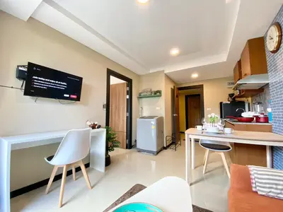 a kitchen with a table and chairs and a tv on the wall at Rawai Beach - 1 BR Cozy Condo in Nai Harn Beach