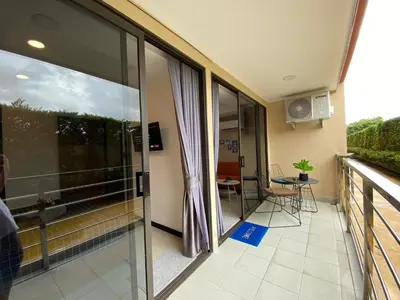a balcony with glass doors and a table and chairs at Rawai Beach - 1 BR Cozy Condo in Nai Harn Beach