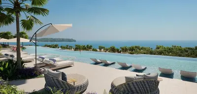 a swimming pool with lounge chairs and the ocean at Laguna Beachfront 3BR Cozy Condo in Bang Tao Beach