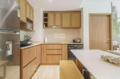 a kitchen with wooden cabinets and a white counter top at Laguna Beachfront 3BR Cozy Condo in Bang Tao Beach