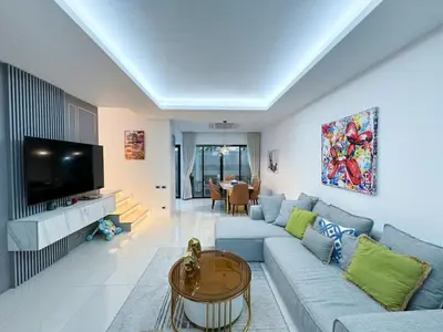 a living room with a blue couch and a tv at Townhouse Bellano 3BR FamilyLaguna Park Bang Tao in Laguna Phuket