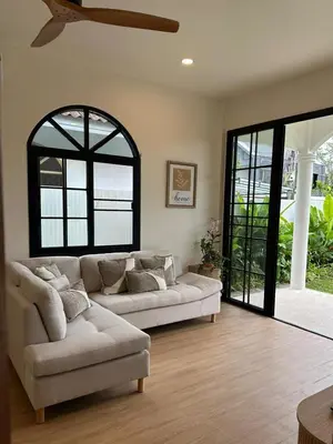 a living room with a couch and a window at Chalong Home Phuket in Phuket Town