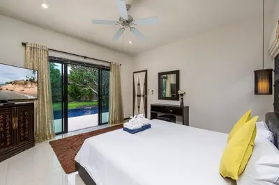 a bedroom with a white bed and a flat screen tv at Villa Haeata 3BR Private Pool Nai Harn Beach in Nai Harn Beach