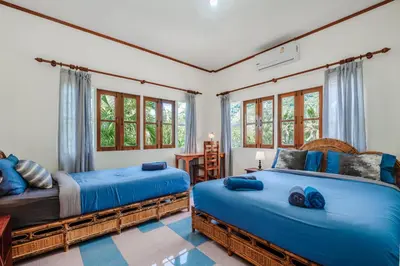 two beds in a room with windows at Tranquility Haven Villa, Kata Beach in Kata Beach