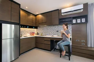 a woman sitting on a chair in a kitchen at Tropical Kamala Hill View 1 BR CTG P407 in Kamala Beach