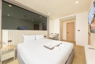 a bedroom with a white bed and a large mirror at Suite Luna Pool and Gym Access The Ozone Condo in Bang Tao Beach