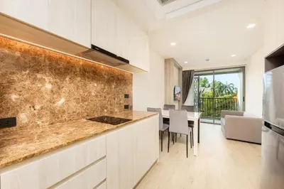 a kitchen with a counter and a dining room at Suite Luna Pool and Gym Access The Ozone Condo in Bang Tao Beach