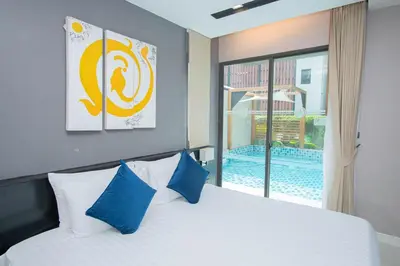 a bedroom with a bed with blue pillows and a window at Beachfront Family Pool 2 Bed Room Patong Phuket in Patong Beach