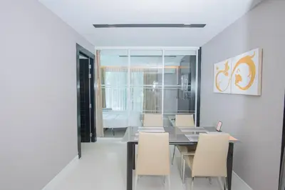 a dining room with a glass table and white chairs at Beachfront Family Pool 2 Bed Room Patong Phuket in Patong Beach