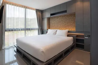 a bedroom with a large bed and a large window at Tropical Kamala Pool View 1 BR CTG B206 in Kamala Beach