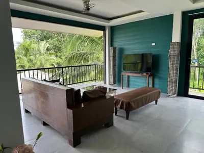 a living room with a couch and a large window at Nankanok Resort in Ko Yao Noi