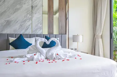 two white swans making a heart shape on a bed at Breeze Villa - Luxury Relaxation in Phuket in Ban Thalat Choeng Thale