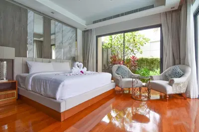 a bedroom with a white bed and two chairs at Breeze Villa - Luxury Relaxation in Phuket in Ban Thalat Choeng Thale