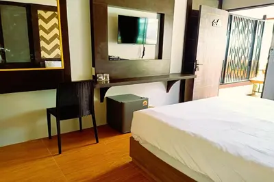 a bedroom with a bed and a chair and a mirror at Resort Thalang in Phuket